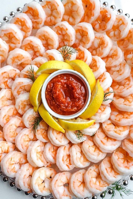 a plate of shrimp with slices of lemon and cocktail sauce